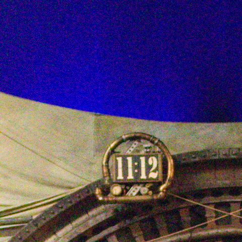 A clock's numerals over a circus ring at ISO 12800, at 1:1, as the camera recorded it